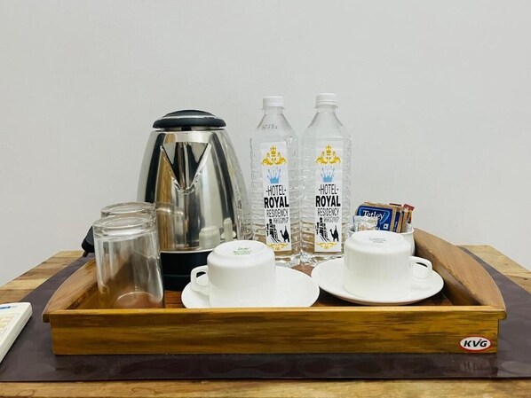Un plateau avec une cafetière, deux bouteilles d’eau, deux tasses et une boîte de mouchoirs.