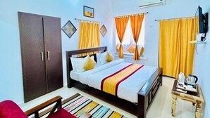 Een hotelkamer met een bed, een garderobe, gordijnen, een televisietoestel en een klein tafeltje met spullen erop.