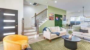 Ein modernes Wohnzimmer mit Treppe, einer Sofagarnitur, einem Couchtisch und einem leuchtend gelben Sessel.