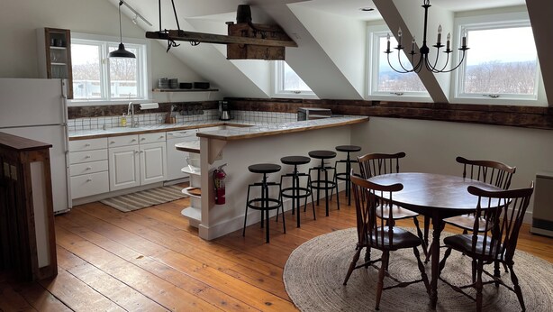 Una cocina moderna con una isla central, suelo de madera y una zona de comedor con una mesa redonda y sillas.