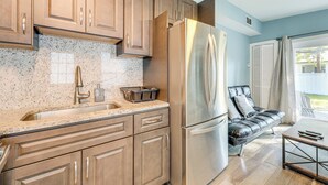 Una cocina con armarios de madera, un refrigerador de acero inoxidable, una encimera de granito y un horno empotrado.