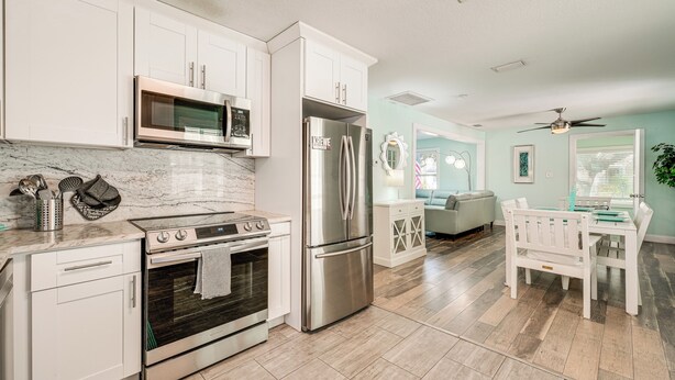 A modern kitchen with white cabinets, stainless steel appliances, and a marble countertop. - 6 Mi to Raymond James Stadium: Tampa Retreat! (Tampa)