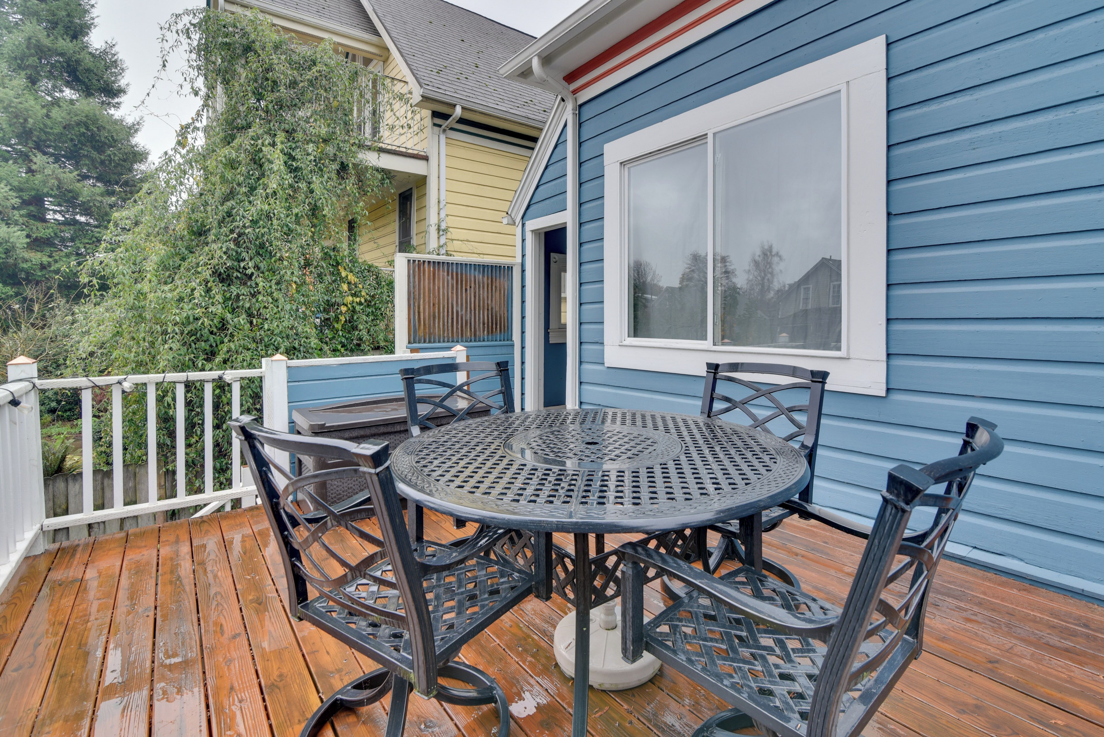 A wooden deck with a round metal table and four chairs.