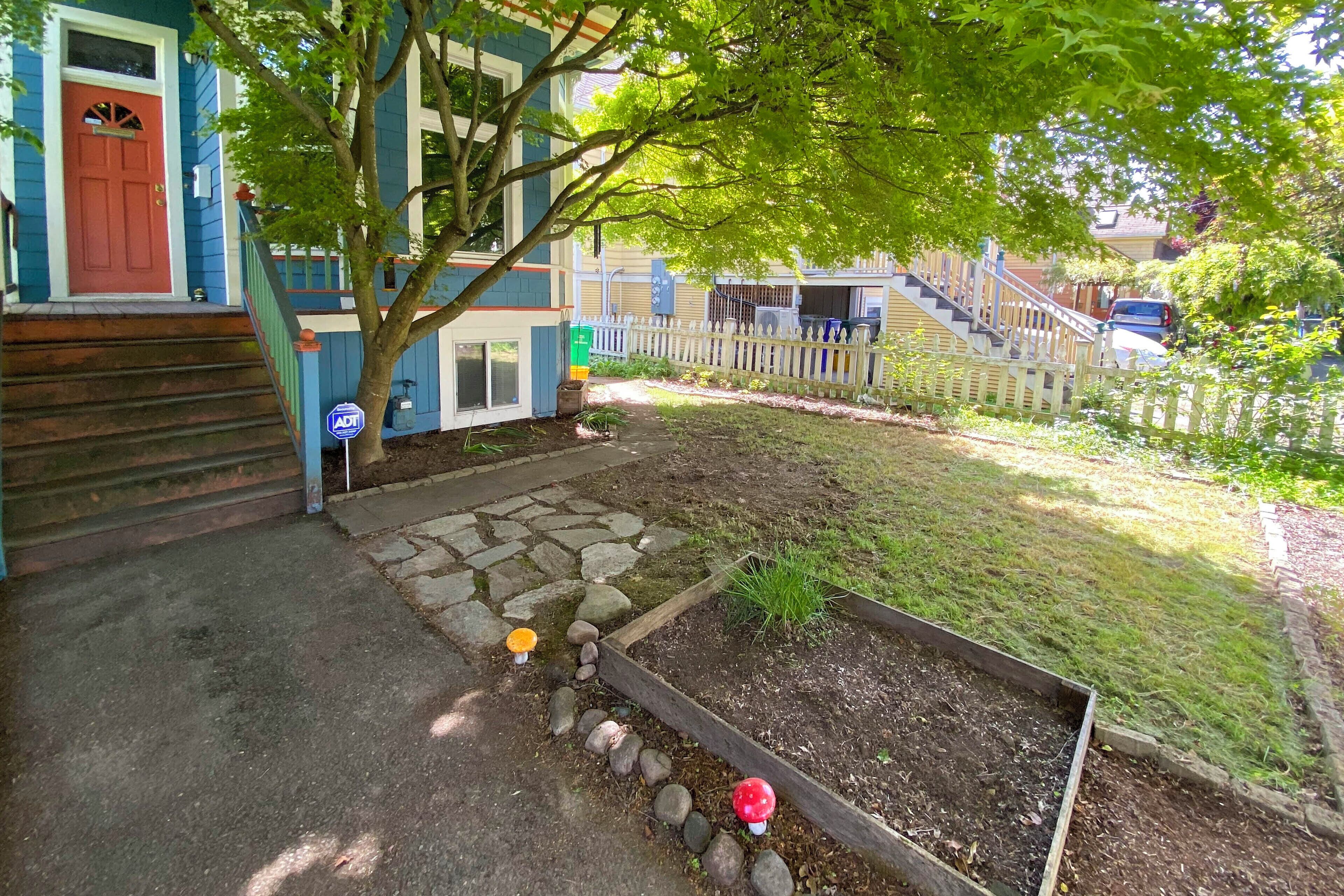 A residential property with a front yard, a wooden deck, and a staircase leading to a second-story entrance.
