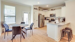 A modern kitchen with white cabinetry, stainless steel appliances, and a central island with bar stools. - 7 Mi to Lackland Afb: Family Home w/ Patio & Yard! (San Antonio)