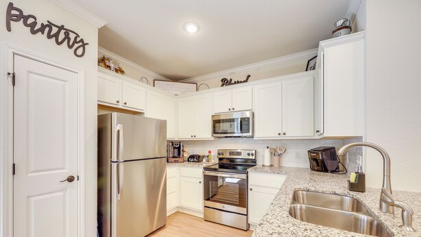A modern kitchen with white cabinets, stainless steel appliances, and a granite countertop. - 7 Mi to Lackland Afb: Family Home w/ Patio & Yard! (San Antonio)