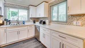 A modern kitchen with white cabinets, a granite countertop, and a coffee station. - Florida Adventure Hub Near Top Attractions & Lakes (St. Cloud)