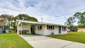 A single-story house with a covered porch, a front yard, and a driveway. - Florida Adventure Hub Near Top Attractions & Lakes (St. Cloud)