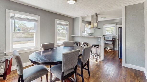 A modern kitchen with a dark wooden table and chairs, a white ceiling, and a view of the outside through large windows. - Group-friendly Michigan City Home Near Beach! (Michigan City)