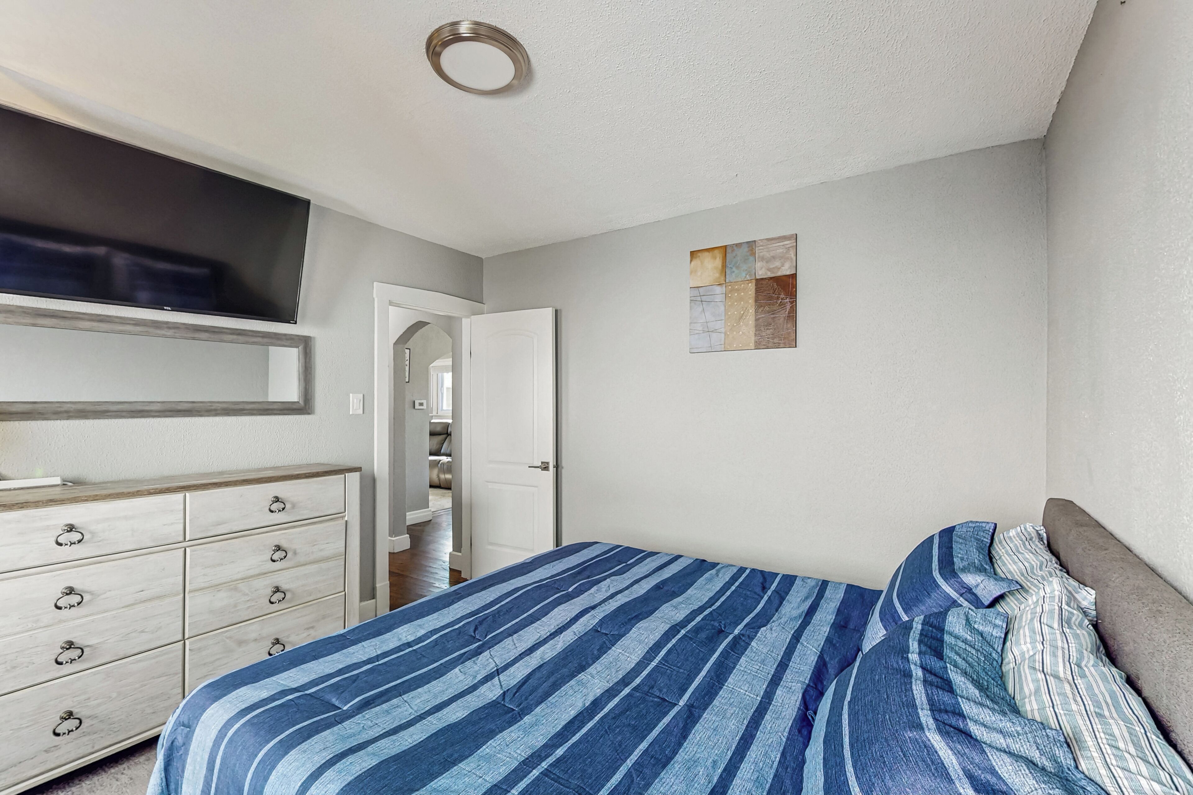 Un dormitorio con cama, cómoda y una puerta que da a un armario.