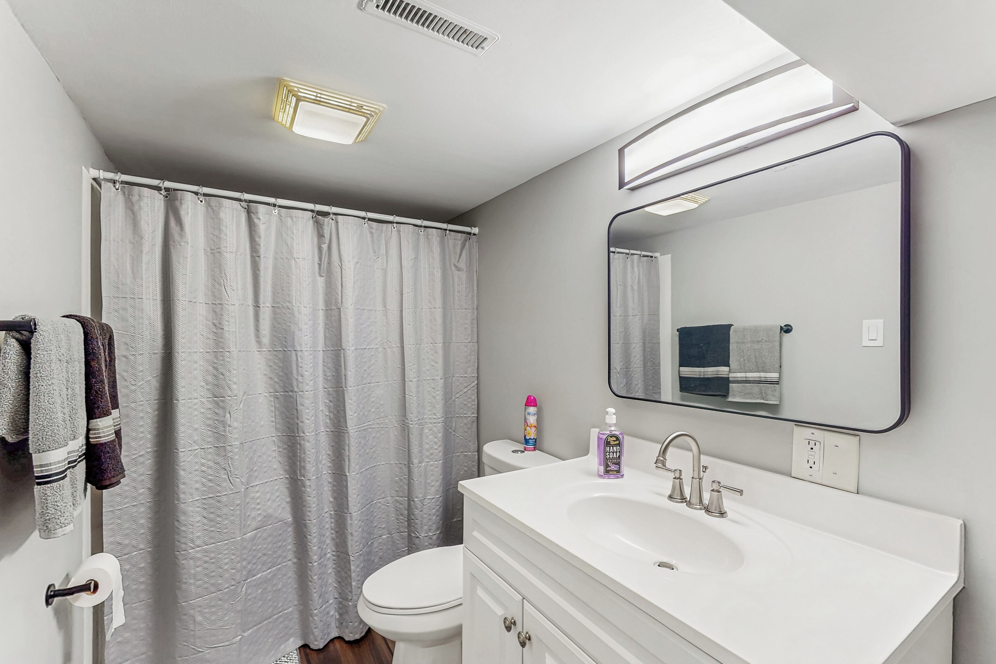 A bathroom with a toilet, sink, and shower curtain.