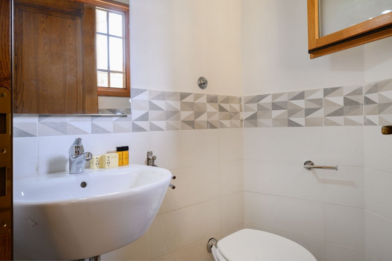 A bathroom with a white sink, a toilet, and a wooden cabinet above the sink.
