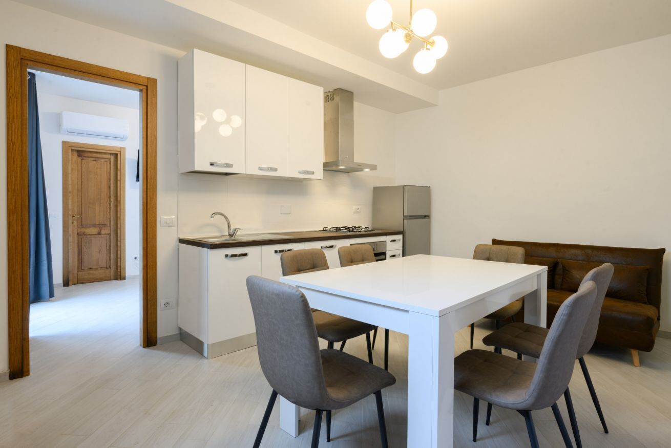 Een moderne keuken met witte kasten, een centraal eiland en een eethoek met vier stoelen.