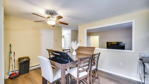 A dining area with a ceiling fan, wooden dining table, and chairs. There is a trash can and a mop in the corner. - < 1 Mi to Beach! Quaint Norfolk Duplex w/ Yard (Norfolk)