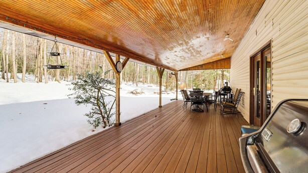 A covered wooden deck with a grill and outdoor seating area, overlooking a snowy landscape. - 4 Mi to Camelback! Group-friendly Poconos Cabin (Tannersville)