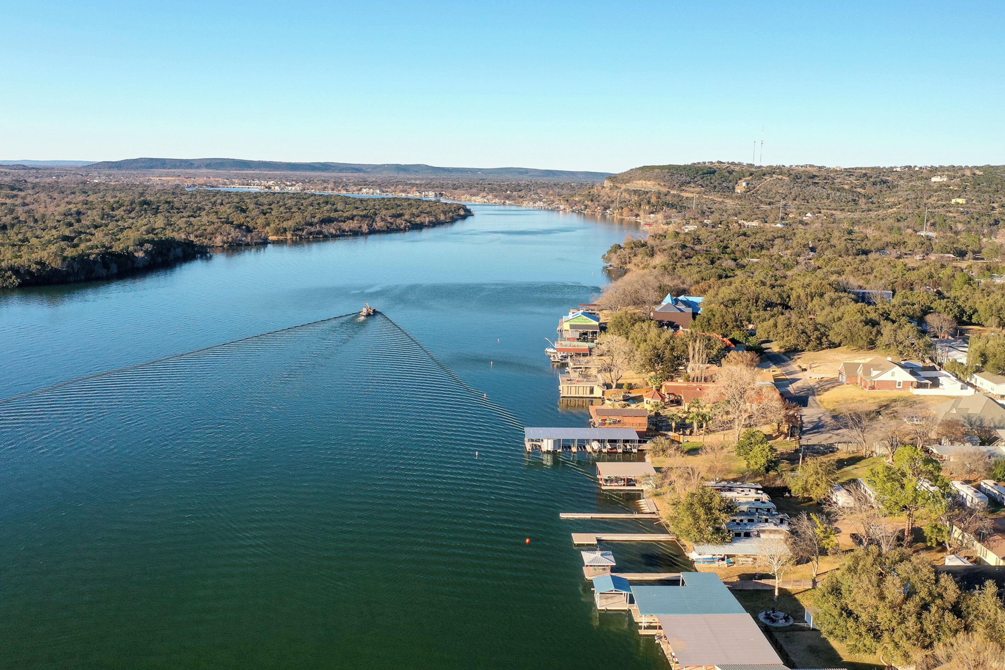 Um rio com um barco, cercado por edifícios residenciais e vegetação.