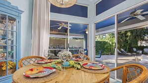 A round wooden table with woven placemats, surrounded by wicker chairs. - Bike to State Park: Family Getaway in Naples (Naples)