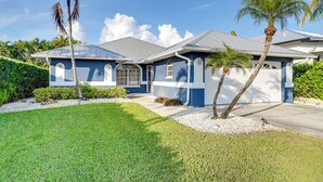 A two-story house with a blue exterior, a grey roof, and a well-maintained lawn with palm trees. - Bike to State Park: Family Getaway in Naples (Naples)