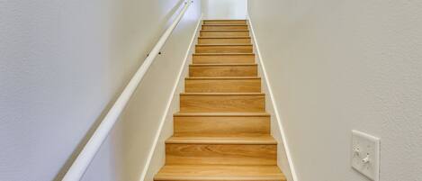 A wooden staircase with white walls and a handrail.