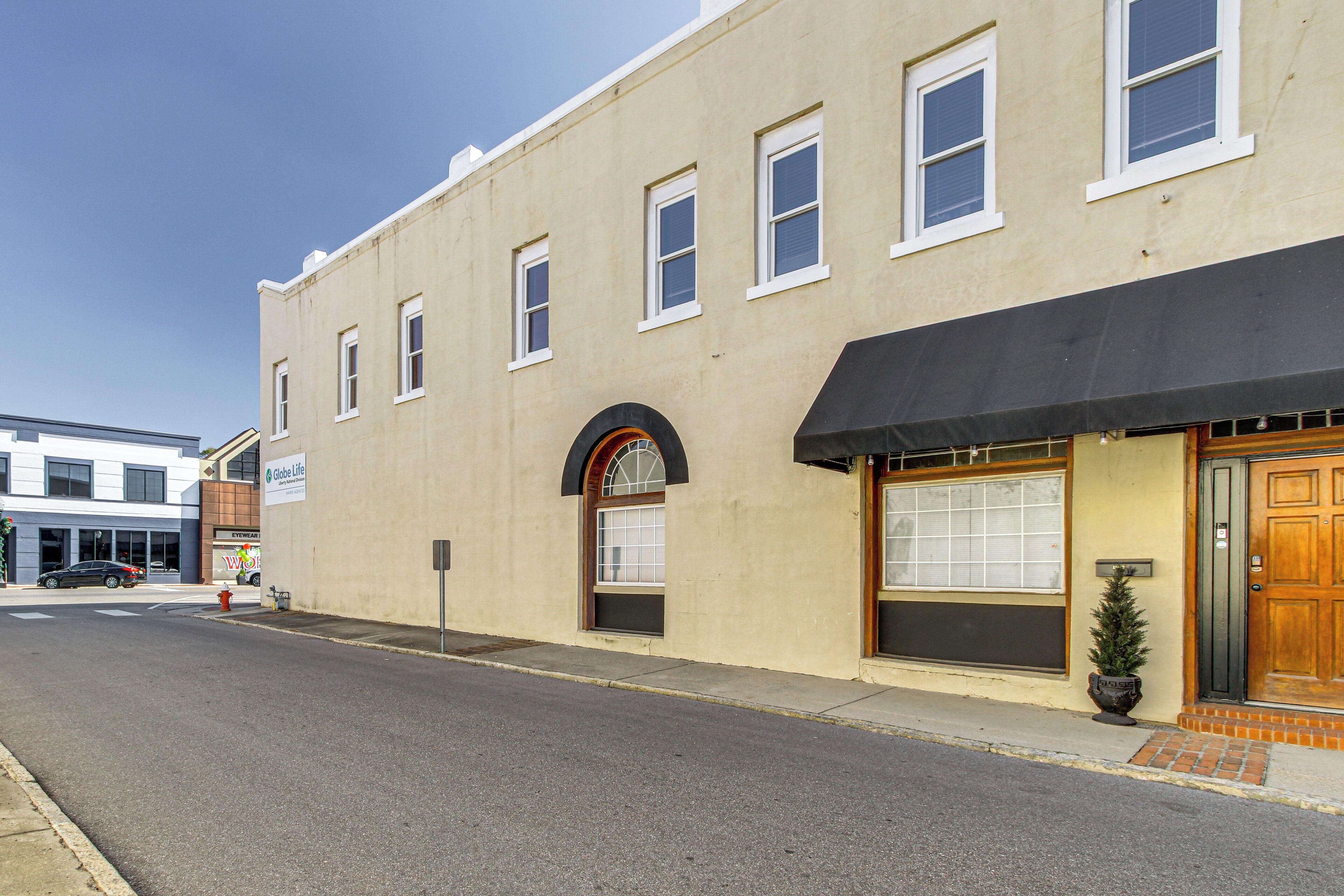 A two-story building with a black awning over the entrance, a small potted plant, and a mailbox.