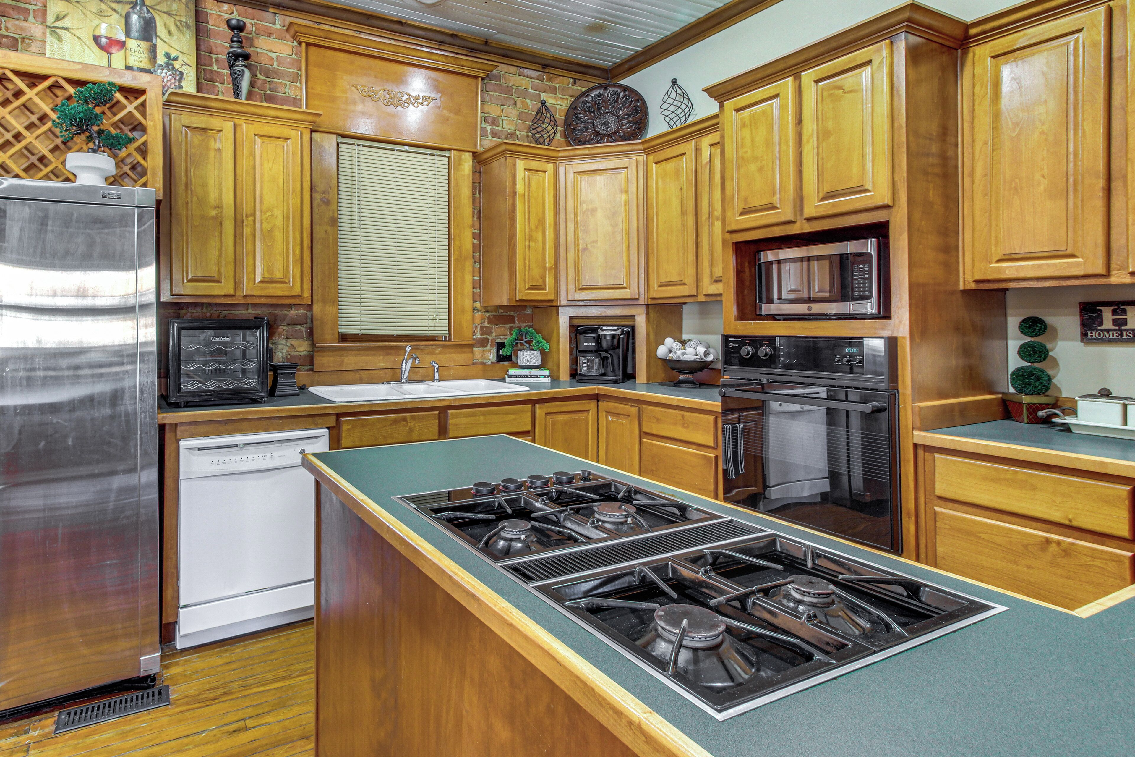 A kitchen with wooden cabinets, a stainless steel refrigerator, a dishwasher, a stove, a microwave, and a sink.