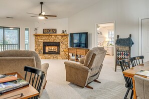 A living room with a stone fireplace, a television, and comfortable seating.