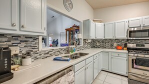 A modern kitchen with white cabinets, a stainless steel sink, and a built-in oven.