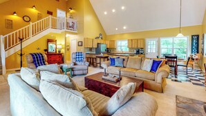 A spacious living room with a high ceiling, a staircase, and a kitchen in the background. - Creekside Seclusion: 'homested Retreat' in Dallas (Dallas)