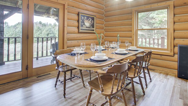 A wooden cabin with a dining table set for six, surrounded by wooden chairs.