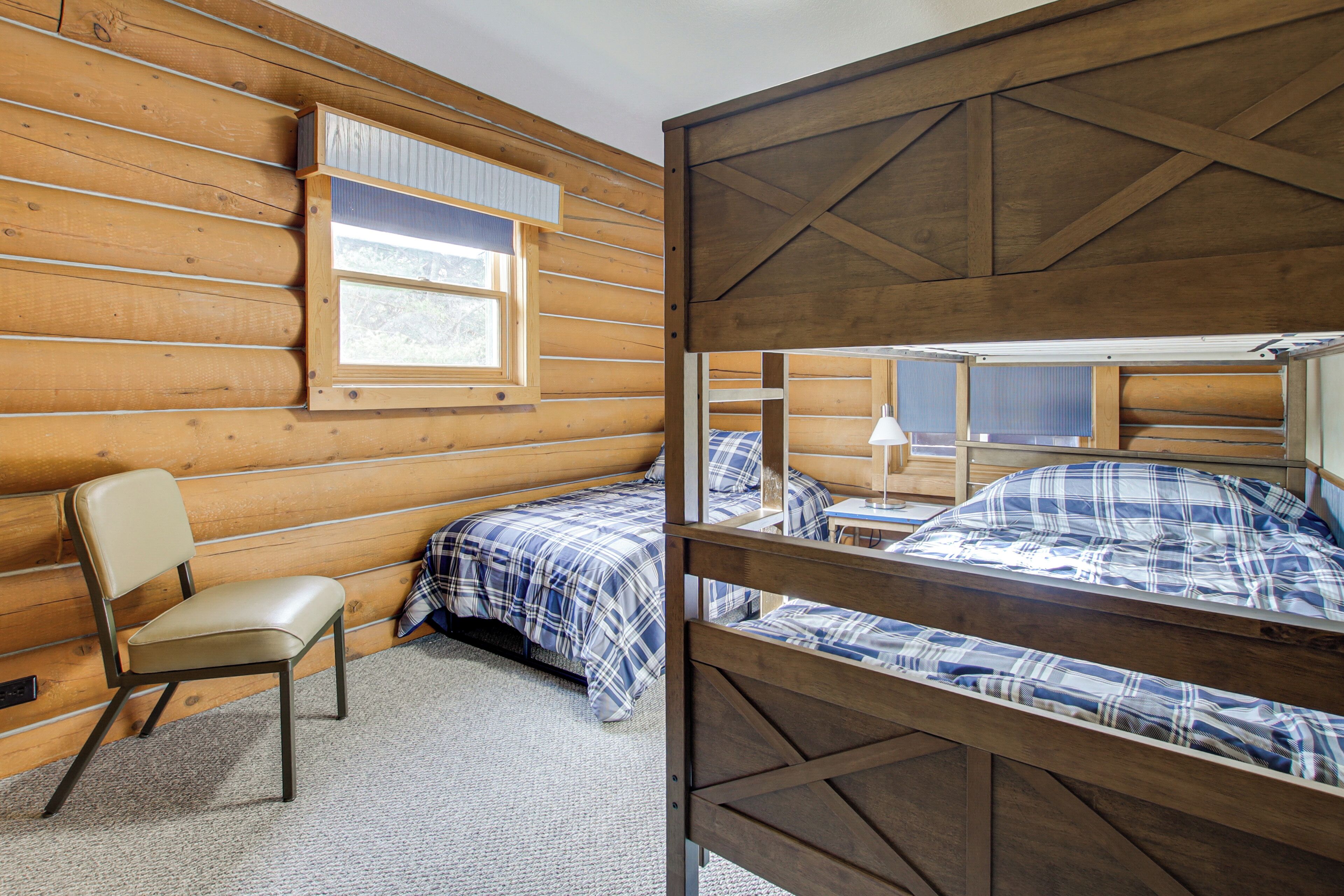 Una habitación tipo cabaña con dos literas, una silla y una ventana.
