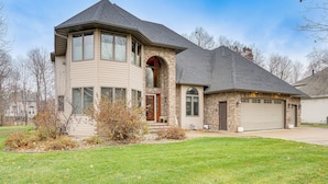 A two-story house with a garage, a large window, and a brick section. - Rare Gem on a Ravine, Family Home in North Mankato (Mankato)