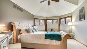 A bedroom with a large bed, a dresser, a bench, and a ceiling fan. - Rare Gem on a Ravine, Family Home in North Mankato (Mankato)