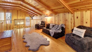 A log cabin interior with a wooden ceiling, a sofa with a 'welcome home' pillow, a fur rug, and a wooden bench. - Bear's Den 2 Mi to Pinetop CC: Ski, Sled, Hike! (Pinetop)