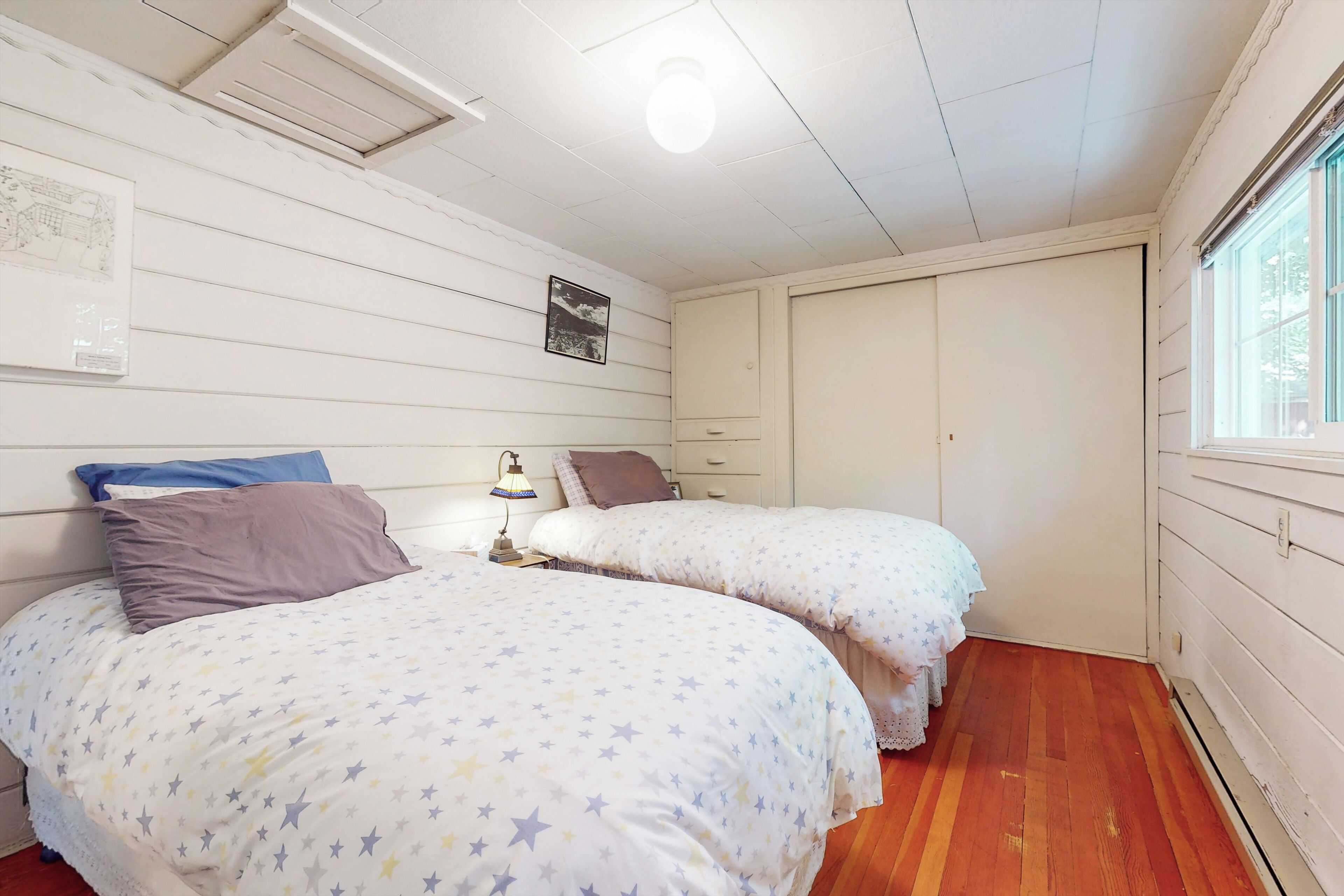 A bedroom with two beds, a window, and a door.