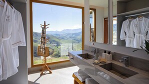 A modern bathroom with dual sinks, a large mirror, and a view of mountains. - Viso Villas Pousada Boutique (Sapucaí-Mirim)