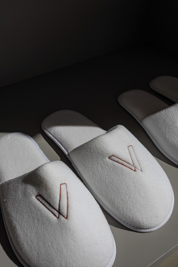 Une paire de pantoufles blanches dont la semelle est ornée d’un motif en forme de V.