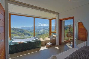 Une chambre moderne avec une grande fenêtre, une baignoire et une vue sur les montagnes.