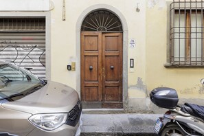 A beige car parked in front of a double wooden door with a metal arch above it. - Pepi Comfort Apartment (Firenze)