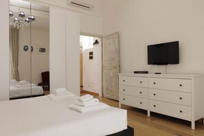 A hotel room with a bed, a dresser, a television, and a mirror. - Pepi Comfort Apartment (Firenze)