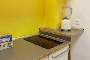 A kitchen with a built-in induction cooktop, a white blender, and a box of biscuits. - Pepi Comfort Apartment (Firenze)
