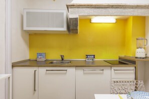 A kitchen with a yellow wall, white cabinets, a microwave, a sink, and a blender. - Pepi Comfort Apartment (Firenze)