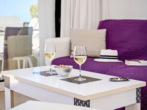 Ein Hotelzimmer mit einem Bett, zwei Gläsern Weißwein, einer Schale Nüsse und einem Hut auf dem Bett.