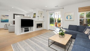 Ein modernes Wohnzimmer mit Kamin, einem grauen Sofa und einem Couchtisch.