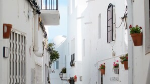 A narrow street with white buildings, a metal gate, and potted plants. - Fantastisches Penthouseapartment by Interhome (Mojácar)