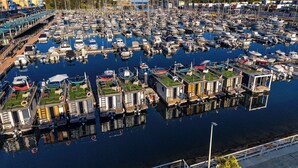 En småbåtshamn med många förtöjda båtar, en gångväg och byggnader med gröna tak.