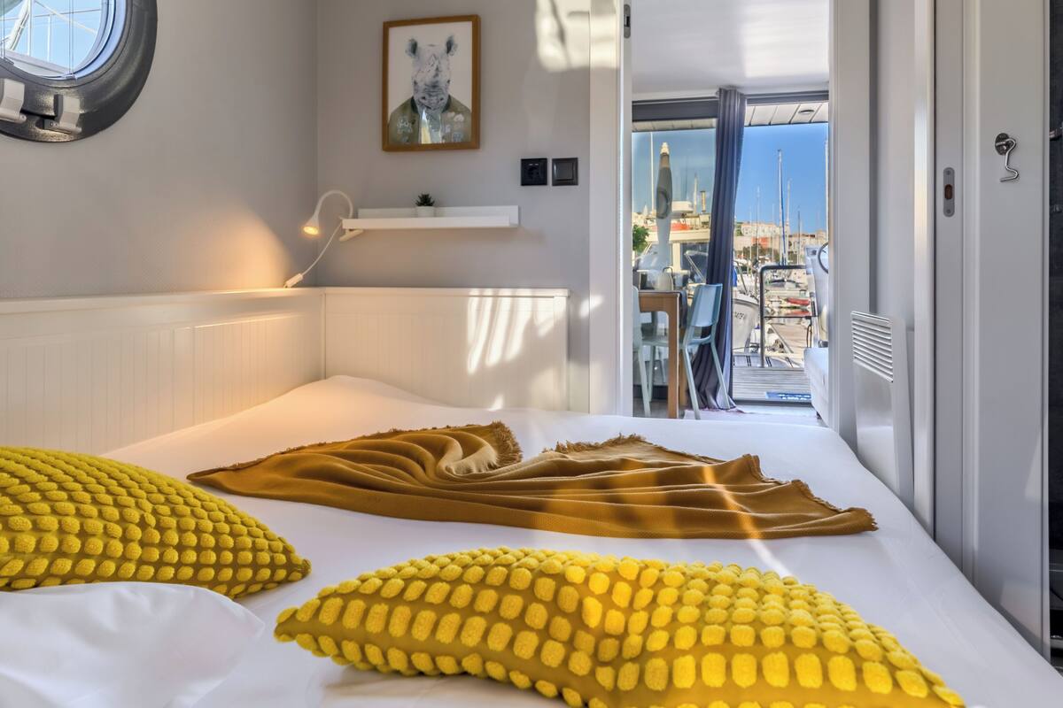 A hotel room with a bed, a window, a door, and a view of the marina.
