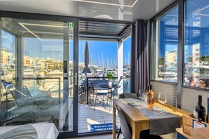 A room with a view of a marina, a table with a bottle and glass, and a door marked 'Welcome'. - The Homeboat Company Albufeira  (Albufeira)