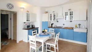 Una cocina compacta con armarios blancos y azules, una mesa de comedor con sillas y un microondas.