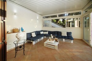 Ein modernes Wohnzimmer mit einem Ecksofa, einem Couchtisch und einer Glastür, die auf einen Balkon führt.