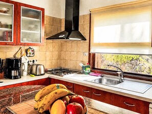 A kitchen with a stove, sink, and a window with a view of greenery. - La Palma by Interhome (El Paso)
